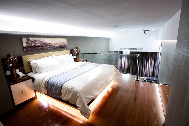 Hotel bedroom with a large bed, wood flooring, and seating area