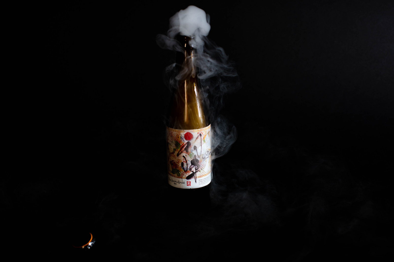 Bottle photographed against a dark background with smoke rising above it