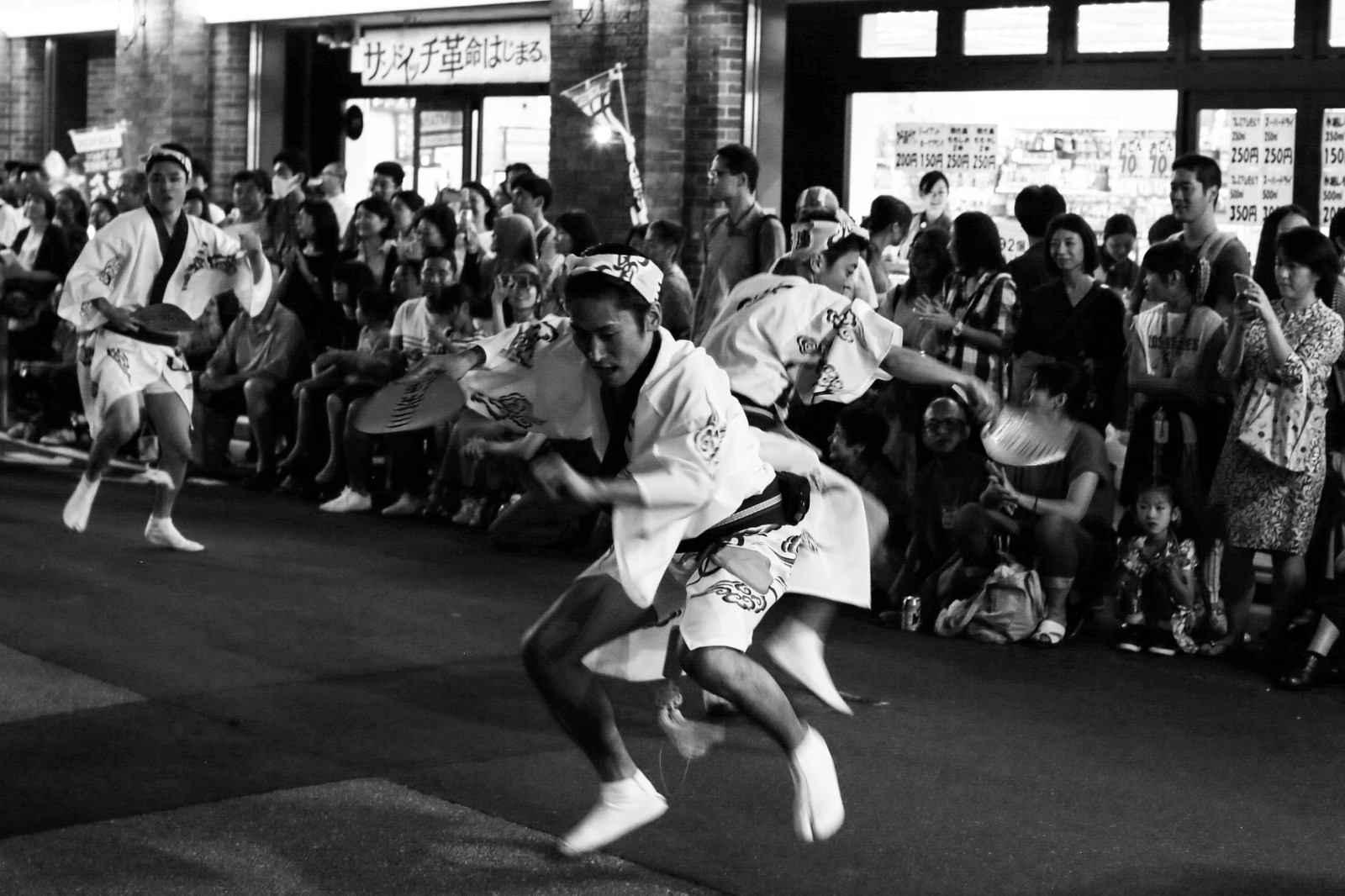 Black-and-white photograph of a street performer in front of a crowd